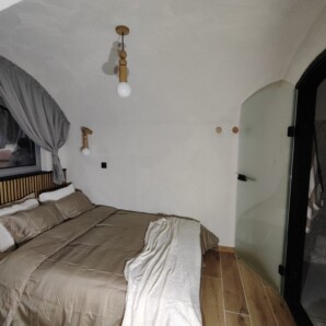 Revonia underground eco-house bedroom interior – arched concrete vault ceiling with wood floors and warm earth tones