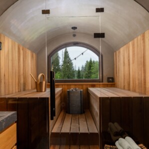 Revonia underground sauna with wooden benches and forest view – earth-sheltered sauna interior with traditional stone stove
